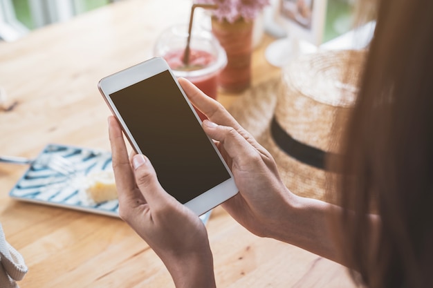 Young woman traveler using smart phone with drinks in cafe while traveling