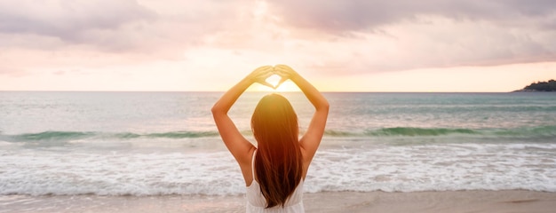 Young woman traveler walking and enjoying beautiful Sunset on the tranquil beach Travel on summer vacation concept Banner panorama