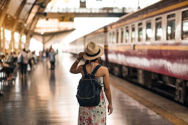 Young woman traveler with backpack waiting for train