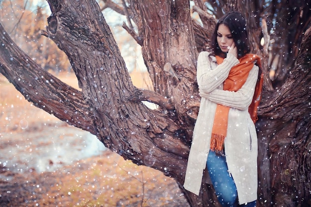 young woman in a trench coat walks in autumn park