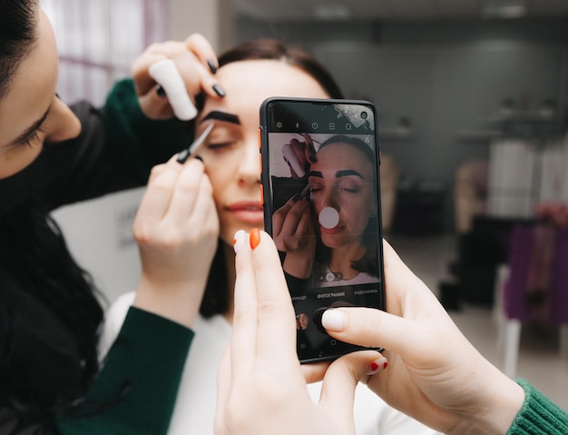 A young woman undergoes an eyebrow correction procedure in a beauty salon closeup the girl paints her eyebrows in the salon