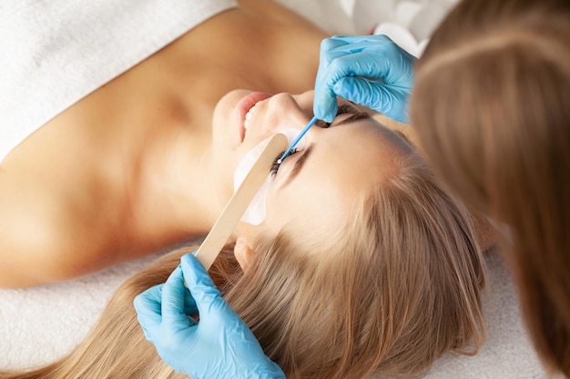 Young woman undergoing eyelash lamination in salon