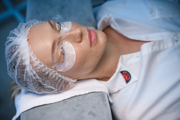 Young woman undergoing procedure of eyelashes lamination in beauty salon, closeup