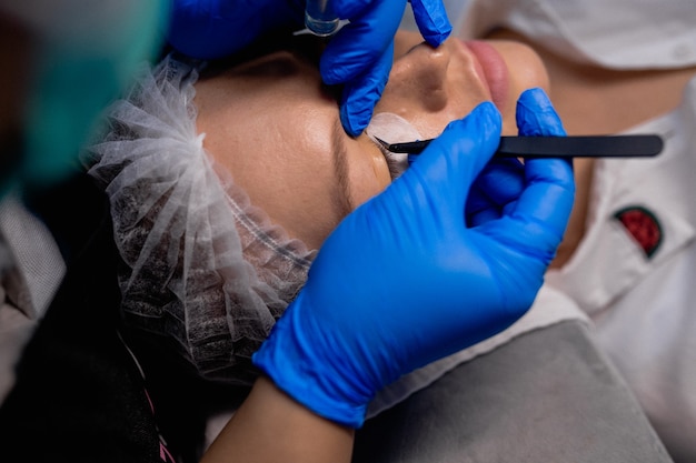 Young woman undergoing procedure of eyelashes lamination in beauty salon