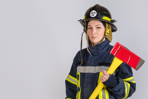 Young woman in uniform of firefighter with axe