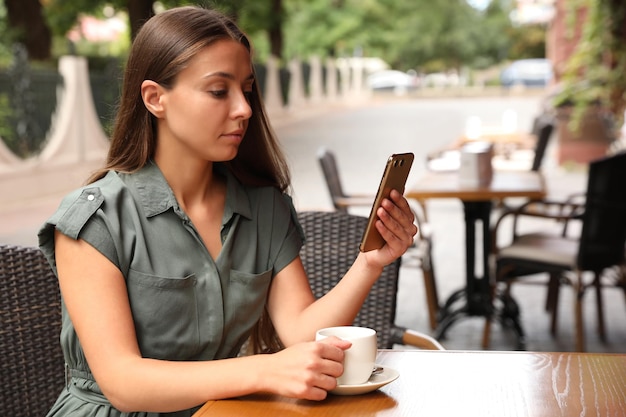 Young woman unlocking smartphone with facial scanner in outdoor cafe Biometric verification