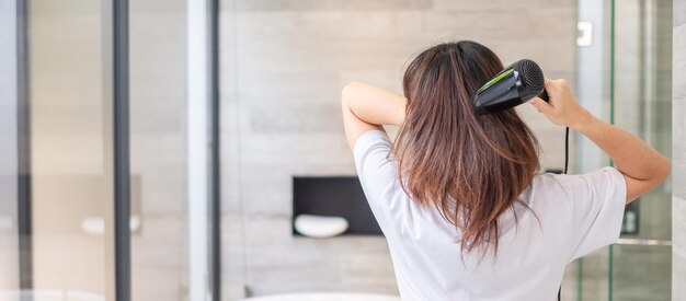 Young woman using hair dryer at home or hotel Hairstyles and lifestyle concepts