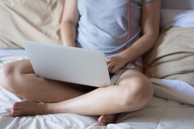 Young woman using her laptop on bed