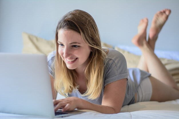 Young woman using her laptop on bed