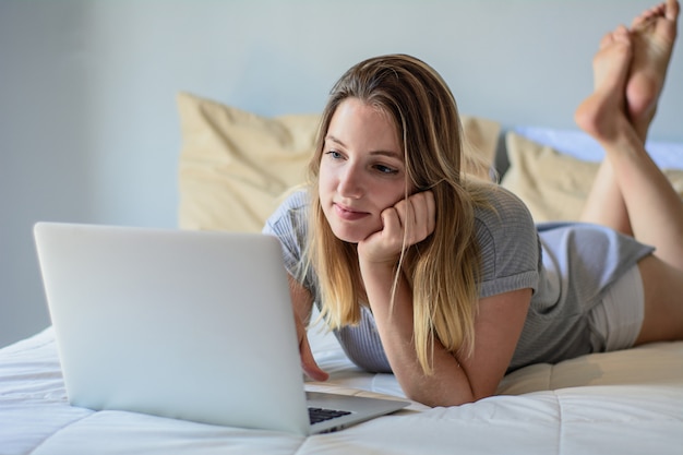 Young woman using her laptop on bed