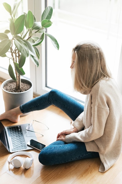 Photo young woman using her laptop while sitting on the floor at home