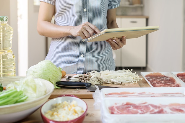 Young woman using her touchpad in the kitchen