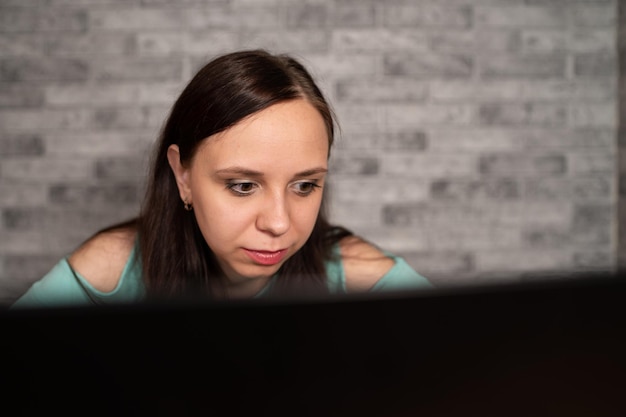 Young woman using laptop computer sitting in front of white brick wall background people and technology lifestyles education business concept