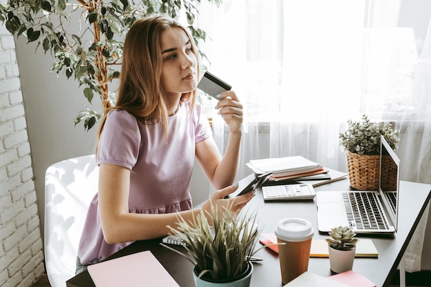 Young woman using laptop computer with credit card in office