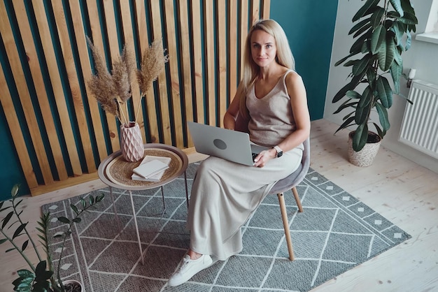 Young woman using laptop sitting at home office desk remote work at home