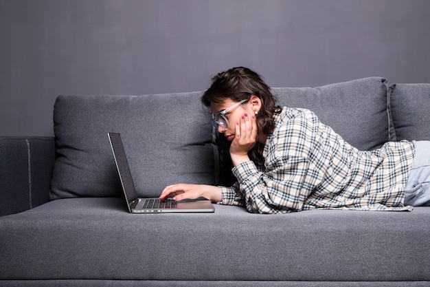 Young Woman using a laptop while relaxing on the couch