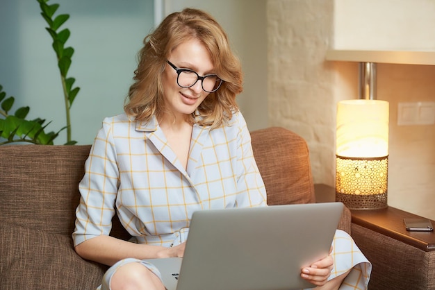 Young woman using laptop while sitting on sofa at home