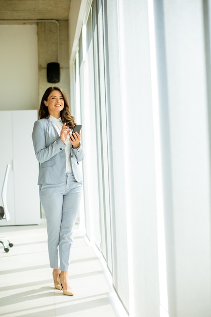 Young woman using mobile phone by the office window