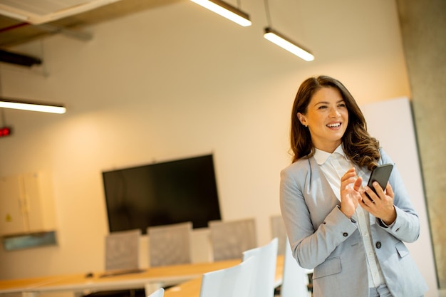 Young woman using mobile phone by the office window