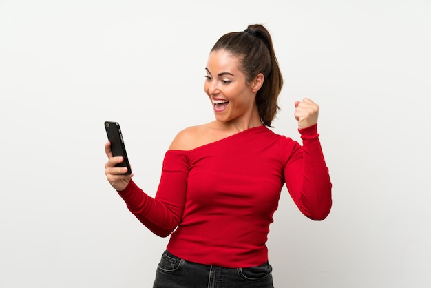 Young woman using mobile phone celebrating a victory