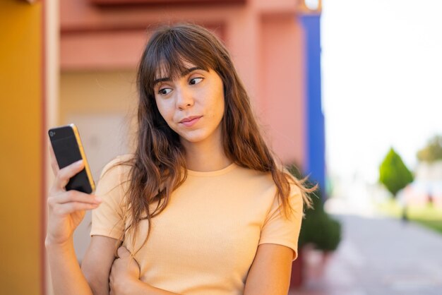 Young woman using mobile phone at outdoors with sad expression