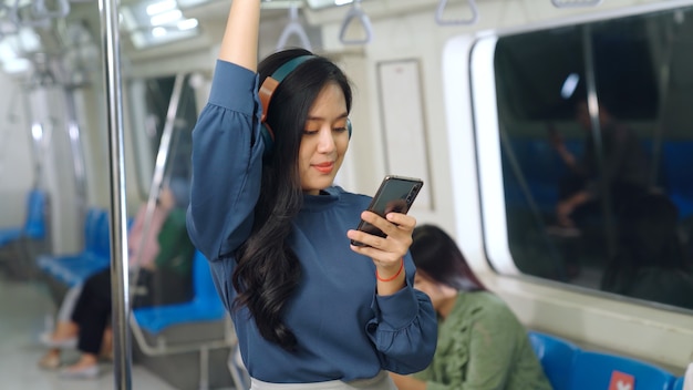 Young woman using mobile phone in public train