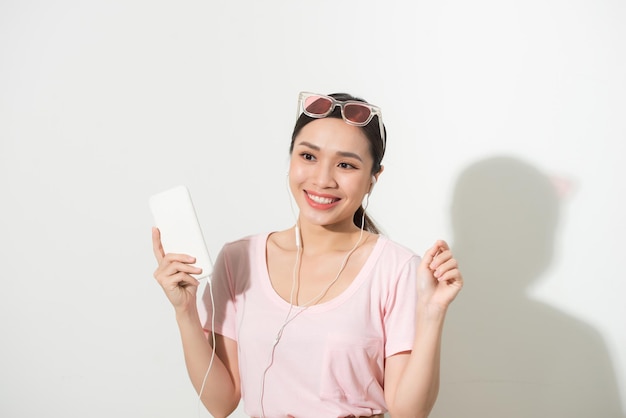 Young woman using phone for listening to music on white background