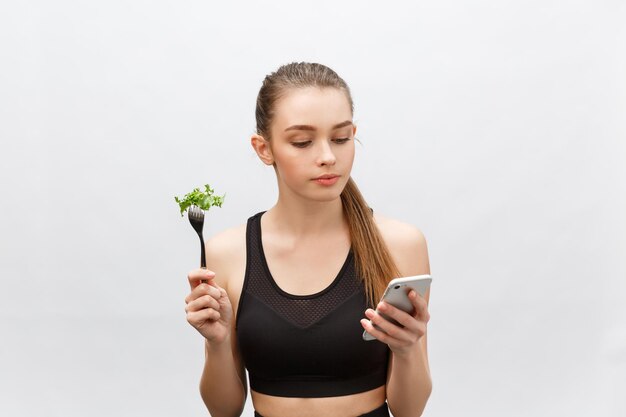 Photo young woman using phone while standing against white background