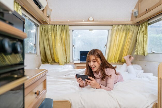 Photo young woman using smartphone on bed of a camper rv van motorhome