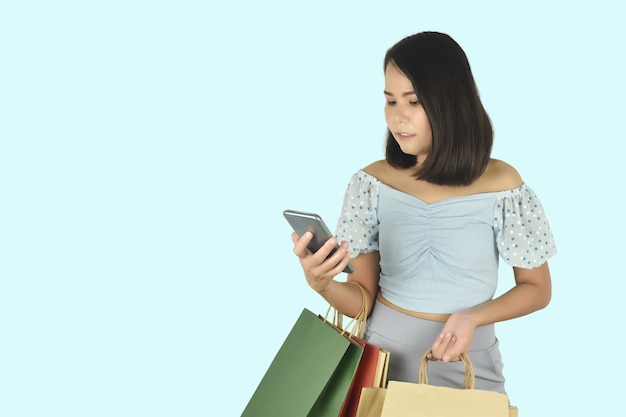 Young woman using smartphone and holding shopping bags in hands Online Shopping App concept