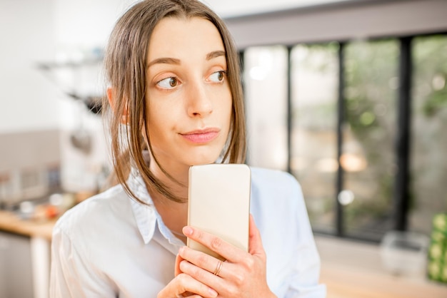 Young woman using a smartphone in the kitchen