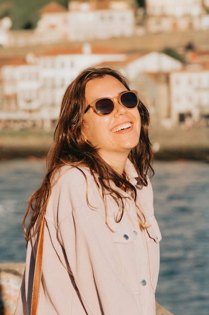 Young woman using sunglasses smiling a lot while touching them, sunglasses concept, summer and travel,copy space