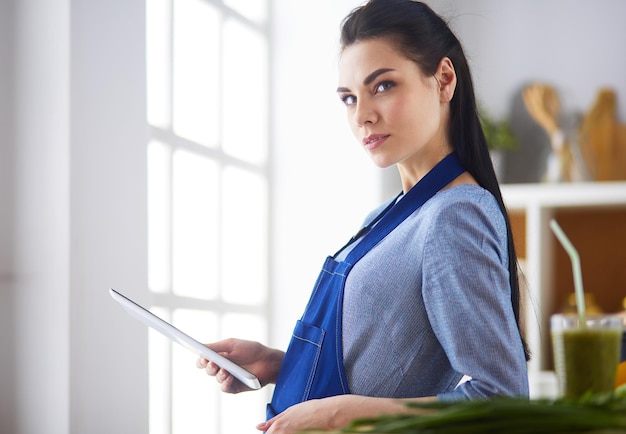 Young woman using a tablet computer to cook in her kitchen