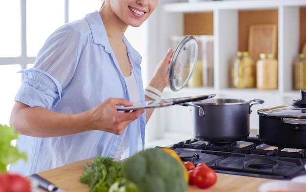 Young woman using a tablet computer to cook in her kitchen