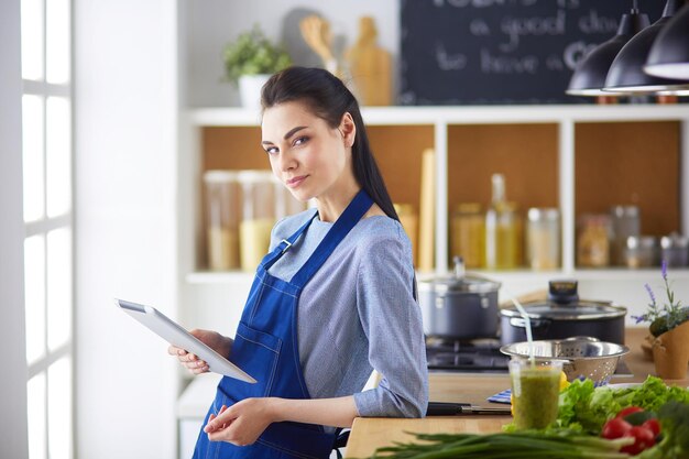 Young woman using a tablet computer to cook in her kitchen