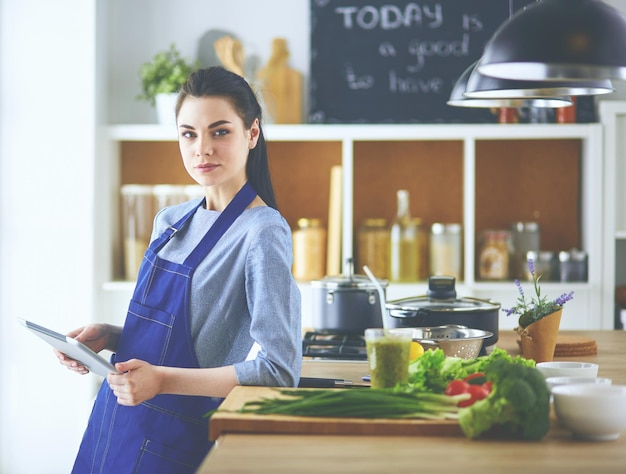 Young woman using a tablet computer to cook in her kitchen