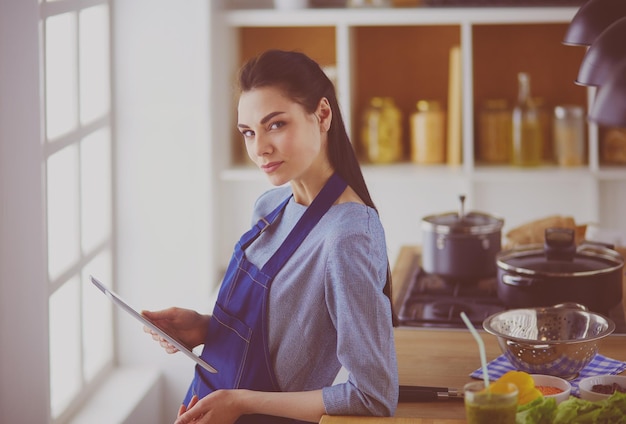 Young woman using a tablet computer to cook in her kitchen