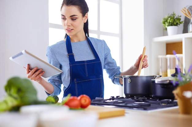 Young woman using a tablet computer to cook in her kitchen