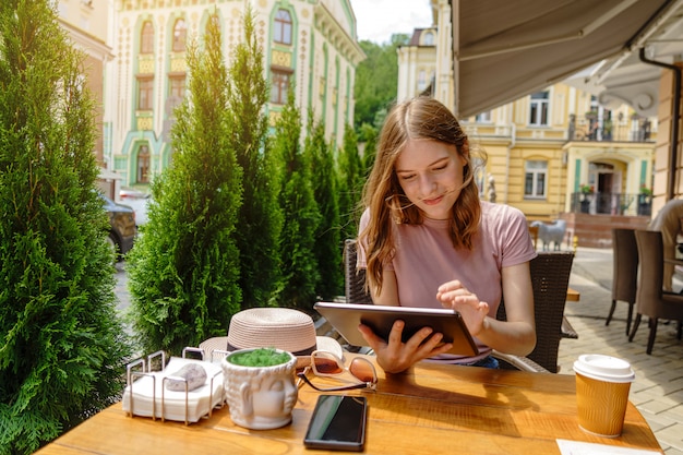 Young woman using tablet pc in a cafe on a summer terrace