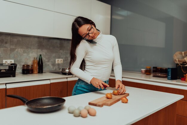 A young woman usinga a smartphone while cooking in the kitchen