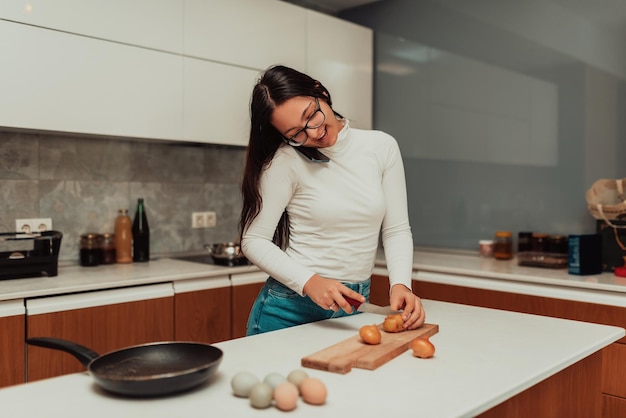 A young woman usinga a smartphone while cooking in the kitchen