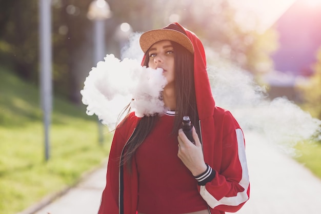 Young woman vape ecig pretty young female in black hat red clothing vape ecig