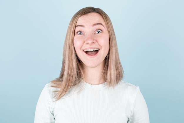 Young woman very surprised . Surprise and shopping concept on blue wall.