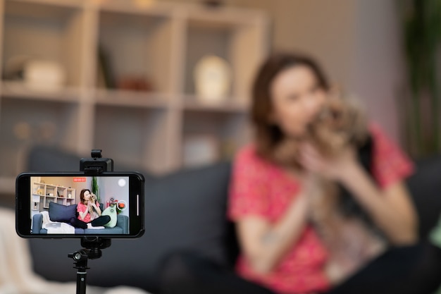 Young woman vlogger influencer sit at home speaking looking at camera and making video conference call record.