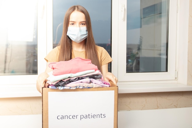 A young woman volunteer with a box of clothes for cancer patients in the help center