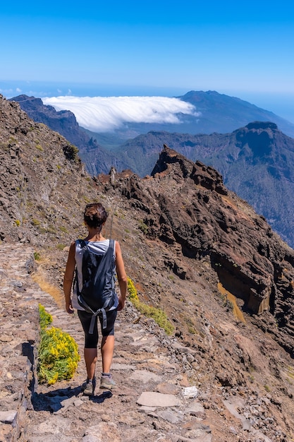 A young woman walking along the path of the Roque de los Muchachos at the top of the Caldera de Taburiente, La Palma, Canary Islands. Spain