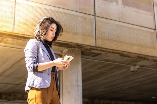 Young woman walking down the street holding cell phone and glass of coffee A Woman Walking Down The Street holding glass Coffee And Using Cell Phone