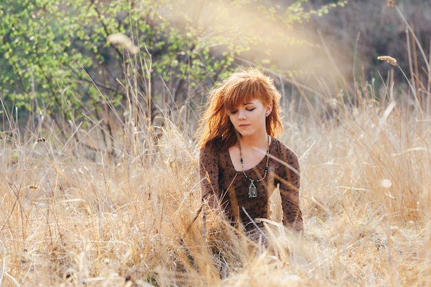 Young woman walking in golden dried grass field