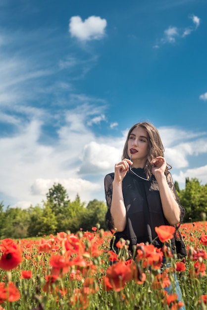 Young woman walking on red poppy field, summer time. Enjoy freedom at nature