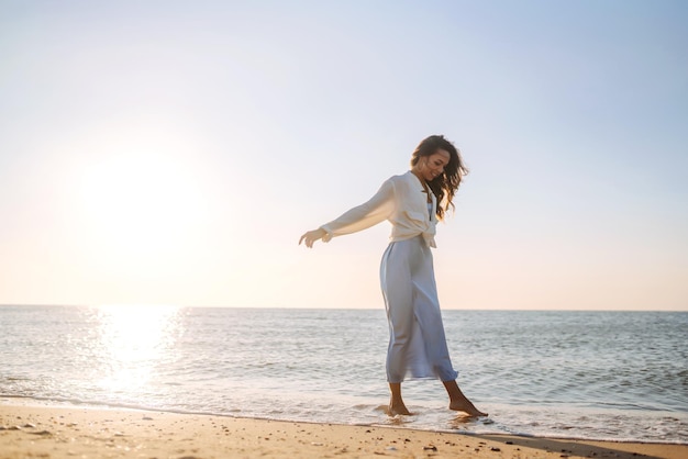 Young woman walking in the sunset on the beach Summer time Travel weekend lifestyle concept